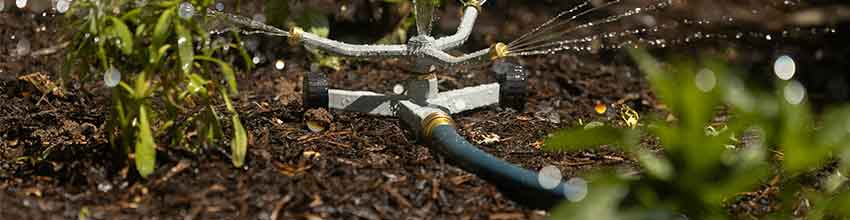 Hagesprinkler, plassert i et bed, spruter vann i tre forskjellige retninger.