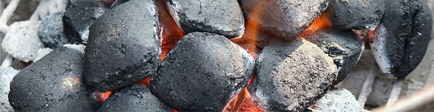 Varme grillkull med glør og flammer i en kullgrill.
