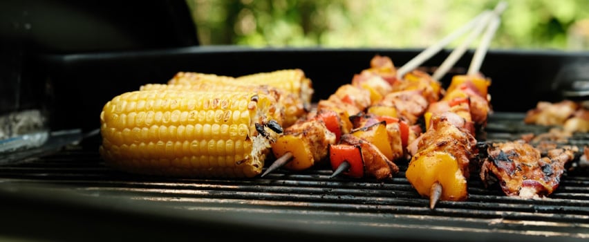 Grillede maiskolber og kyllingspyd med paprika på grillristen, perfekt til sommermåltider og grillopplevelser utendørs.
