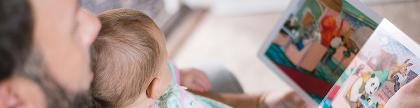 Far med baby på fanget leser høyt – en gaveidé som styrker nærvær og kvalitetstid for nybakte fedre.
