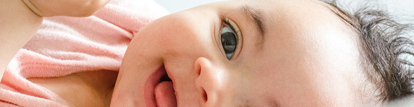 Smilende baby i rosa, gaveidé til jenter som skaper glede og nærhet.