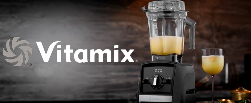 Vitamix blender med gul smoothie i beholder og glas ved siden af logo med sloganet Nye eventyr venter