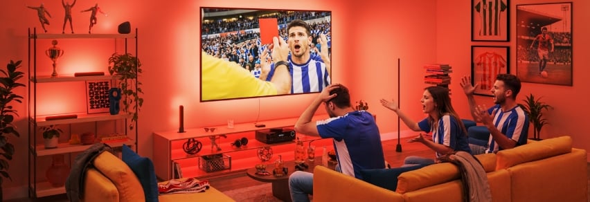 Venner jubler over fotballmål på TV med intens blå WiZ Sports Live-belysning i stuen