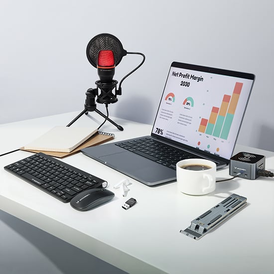 Wozinsky datautstyr med tastatur, mus, mikrofon, laptop-stativ og kaffekopp på lyst skrivebord